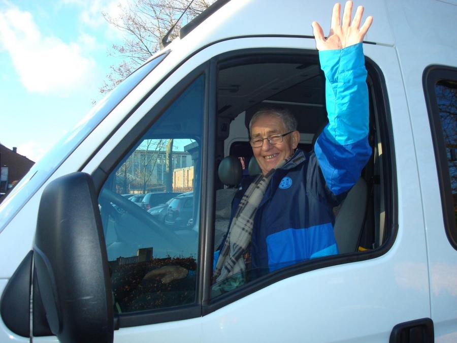 Vrijwillige chauffeur zwaait door raam handicar